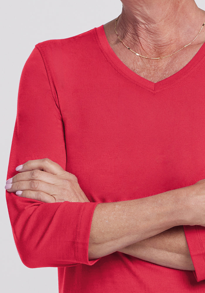 A person in the Woolx Elena 3/4 Sleeve V-Neck - Berry Ice Pop with arms crossed, wearing a delicate necklace.