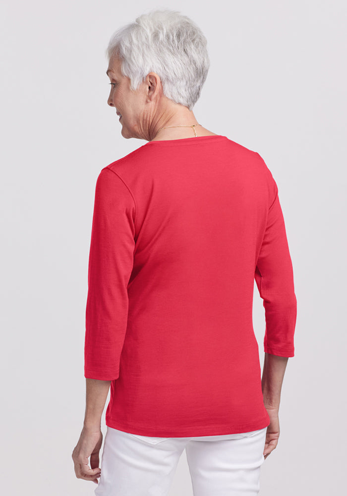 Older woman in a bright berry Elena 3/4 Sleeve V-Neck by Woolx and white pants, short gray hair, facing away.
