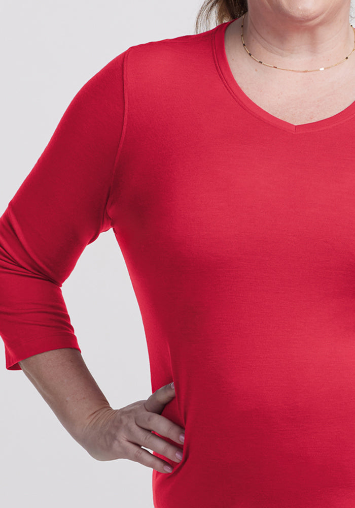 A person in a Woolx Elena 3/4 Sleeve V Neck - Berry Ice Pop, hand on hip, wearing a delicate necklace.