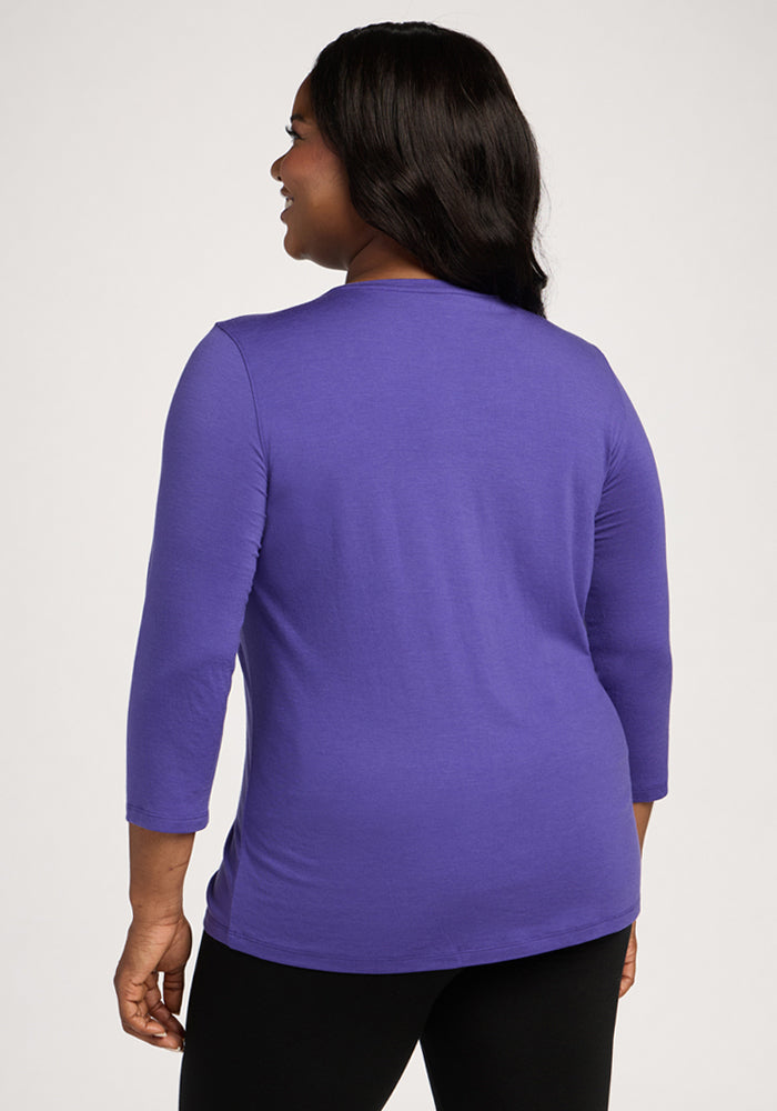 Woman in a Woolx Elena 3/4 Sleeve V Neck - Berry Indigo and black pants stands with her back to the camera.