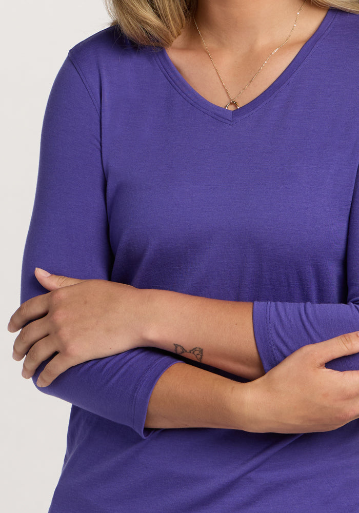 A person in a Woolx Elena 3/4 Sleeve V Neck - Berry Indigo with arms crossed, showing a small forearm butterfly tattoo.
