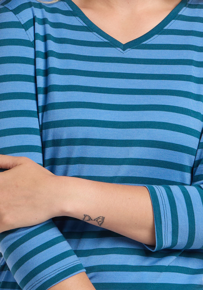 Person in a Woolx Elena 3/4 Sleeve V Neck - Coastal Stripe, arms crossed, butterfly tattoo on wrist.