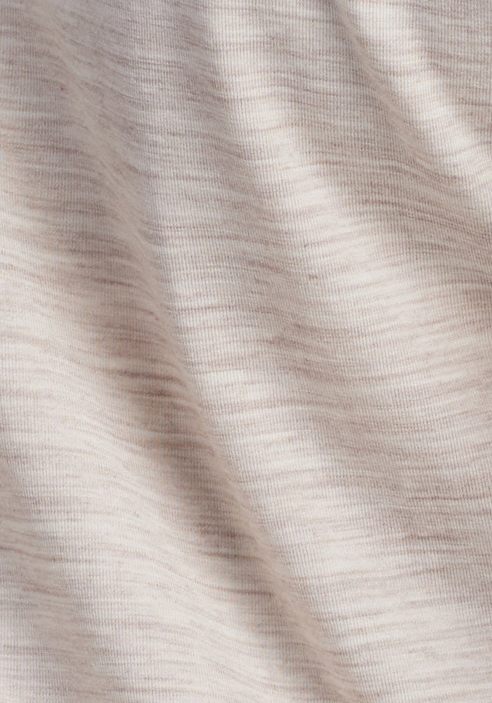 A close-up of cream heather textured fabric with soft, horizontal striations shows a modern chic design. The slight gathering creates subtle shadows, suggesting a soft, knitted merino wool textile ideal for the Woolx Elena 3/4 Sleeve V Neck.