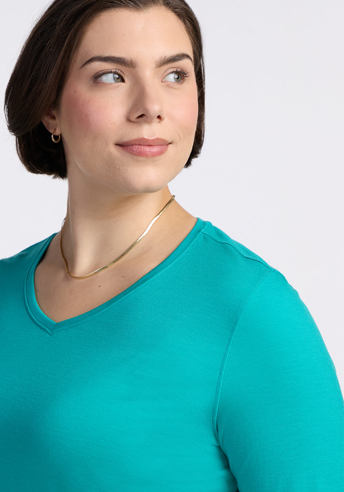Woman with short brown hair in a Woolx Elena 3/4 Sleeve V Neck in Cool Jade, wearing a gold necklace, looking aside.