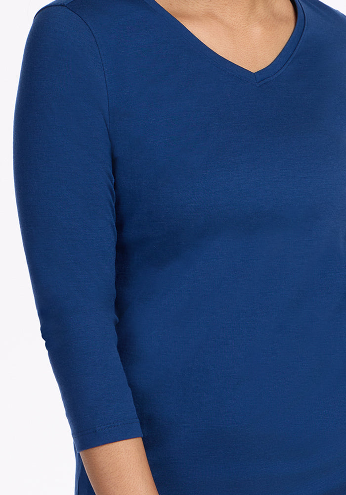 Person wears Woolx Elena 3/4 Sleeve V Neck in Estate Blue, shown shoulder to mid-torso against a white background.