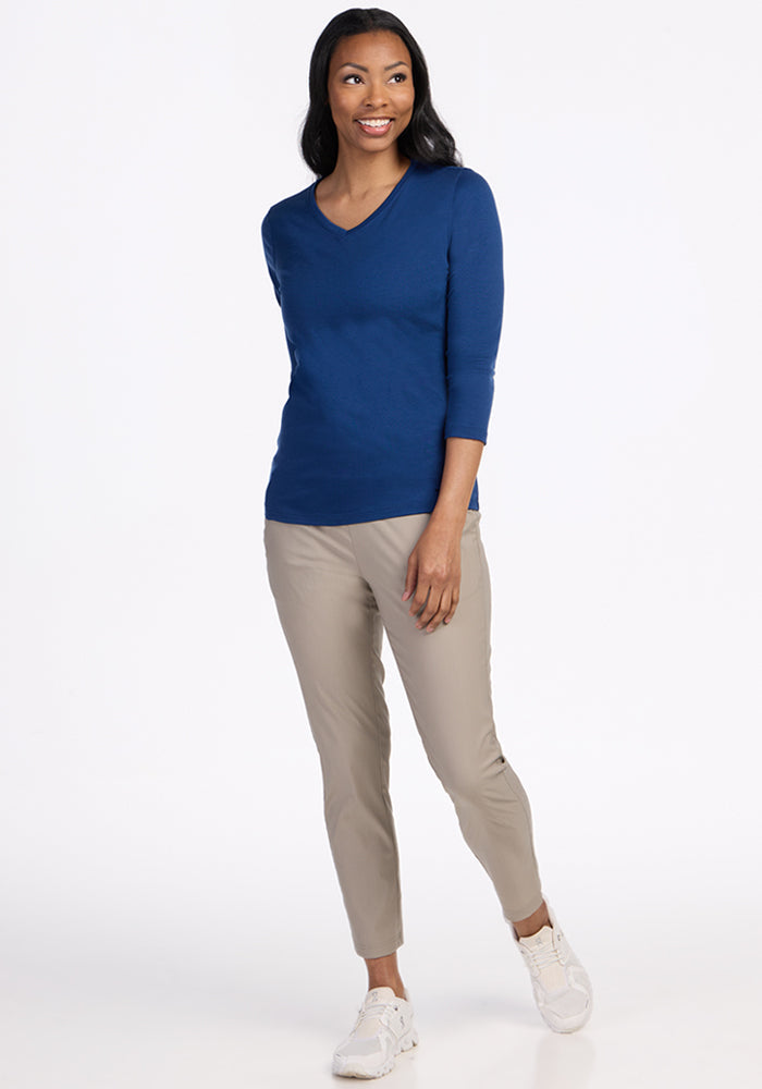 Woman smiling, wearing a Woolx Elena 3/4 Sleeve V Neck in Estate Blue, beige pants, and white sneakers.