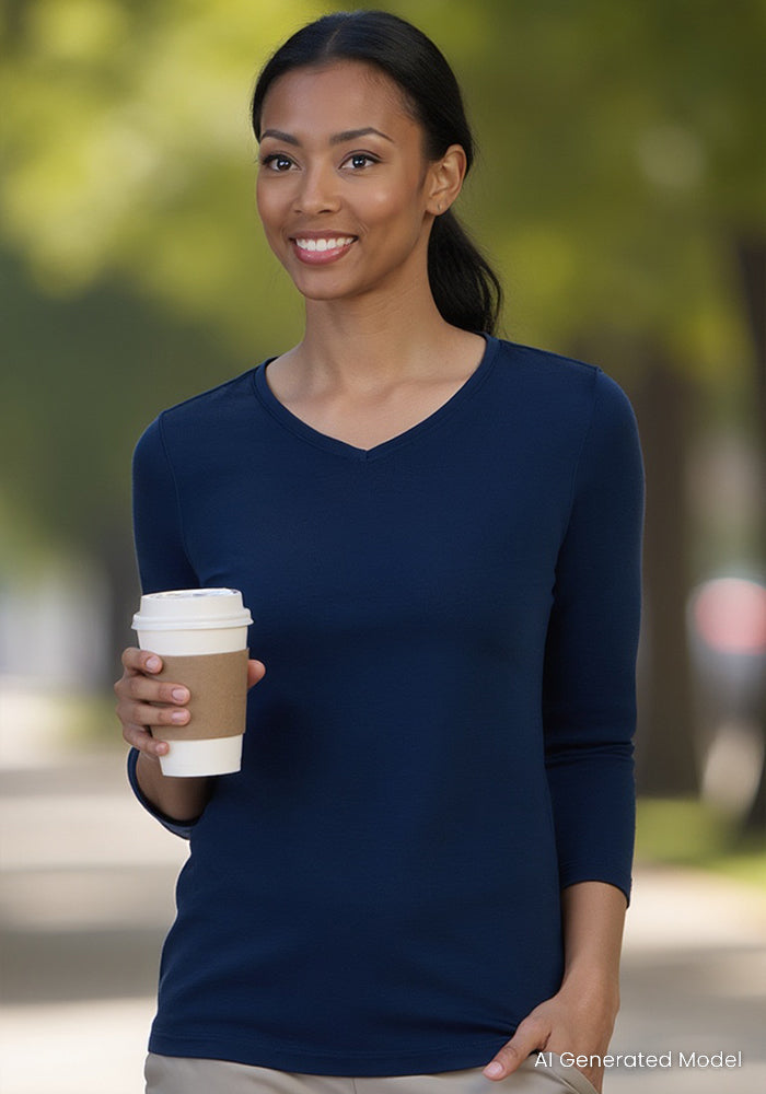 Woman in a Woolx Elena 3/4 Sleeve V Neck in Estate Blue, holding coffee and smiling outside with trees behind her.