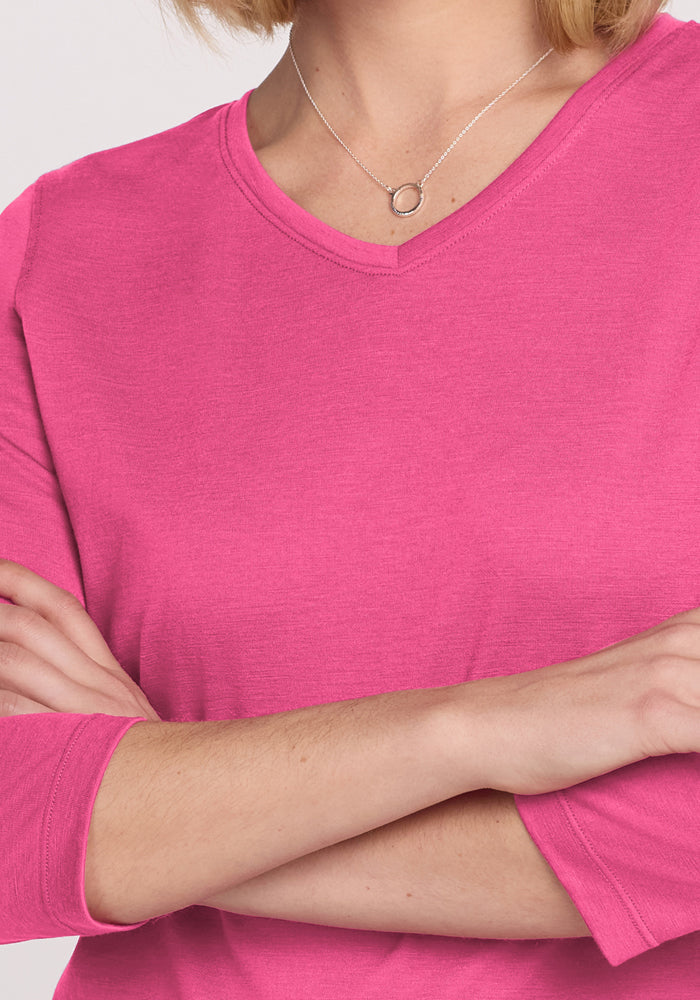 Woman in a Woolx Elena 3/4 Sleeve V Neck in Raspberry Fizz, arms crossed, wearing a silver circular pendant necklace.