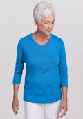 Older woman with short white hair in a Woolx Elena 3/4 Sleeve V Neck - Wave Rider, smiling and looking down.