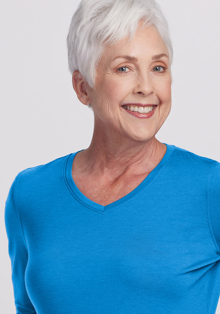 Smiling older woman in a Woolx Elena 3/4 Sleeve V Neck - Wave Rider, with short white hair against a light background.