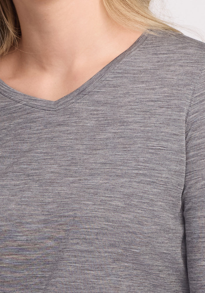 A person with light hair is wearing a Woolx Elena 3/4 Sleeve V-Neck in Graphite Heather. The image highlights the shoulder and upper chest area, showcasing the relaxed fit and soft Merino wool texture.