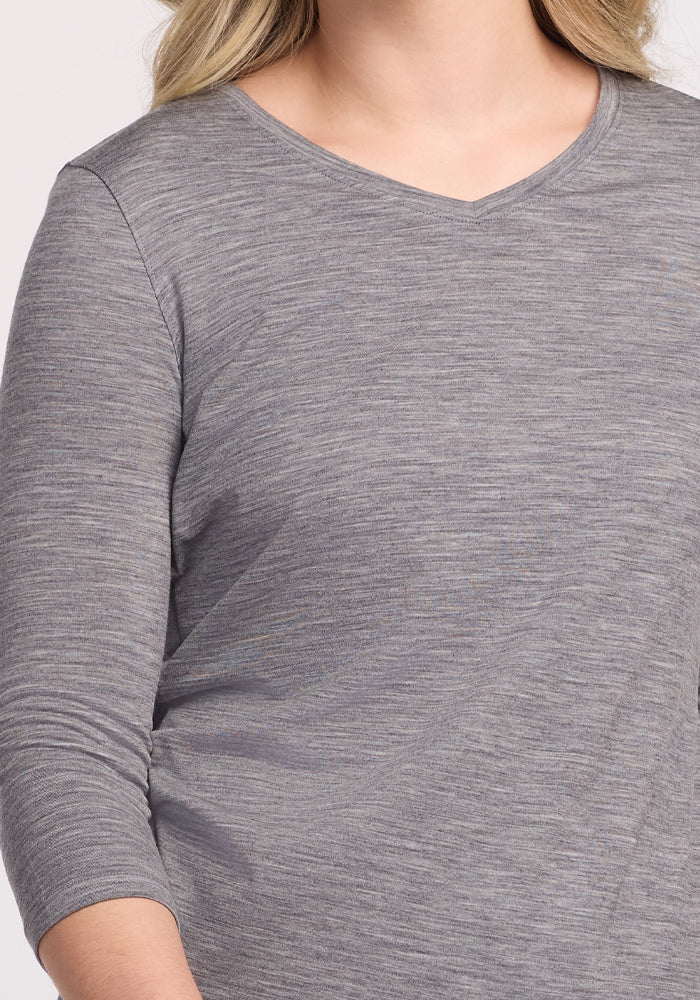 A person wearing the Woolx Elena 3/4 Sleeve V-Neck in Graphite Heather, featuring a relaxed fit and subtle heather pattern, beautifully drapes over the upper torso and part of an arm, blending style with comfort.