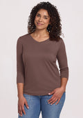Woman with curly hair smiles in a Woolx Elena 3/4 Sleeve V Neck - Peppercorn top and blue jeans against a light background. | Kisha is 5'8", wearing a size M