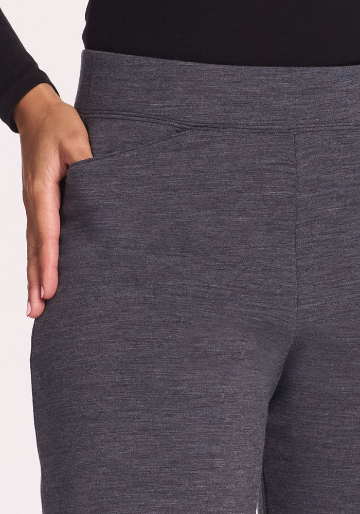 A person wearing Woolx Ellie Wide Leg Pants in Cinder Melange places their right hand into the pocket of the soft, heathered fabric pants.