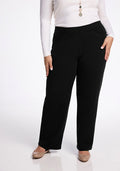 A person wearing Woolx's Ellie Wide Leg Pants Tall in black and a long-sleeved white top stands against a neutral background. They have a necklace with a pendant and are wearing beige flats.
