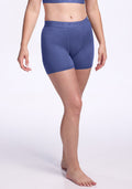 A person stands barefoot in a matching blue sports bra and Woolx Elliott Boyshort - Cloudy Bay, high-waisted and fitted Merino wool boyshorts, against a plain light background. Only the body is visible, not the face. | Ariana is 5'11", wearing a size S