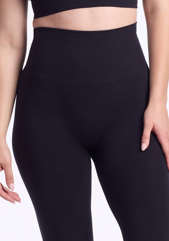 A person wearing Woolx Ellis Seamless Tights - Petite, shown from mid-torso to mid-thigh with hands relaxed by their sides.