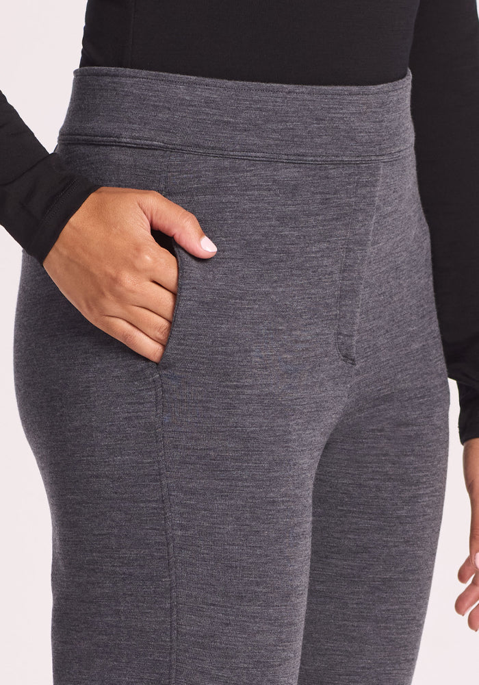 A person in Woolx Emerson Straight Leg Pants - Cinder Melange and a long-sleeve black top stands with one hand in their pocket. The image highlights the waist and upper thigh, showcasing these modern Women’s Work Pants.