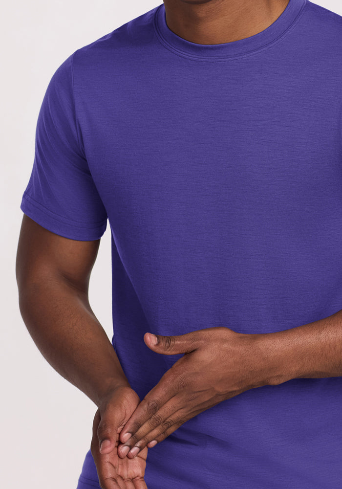 Someone wearing a Woolx Endurance Tee in Berry Indigo with one hand resting over the other at their waist.