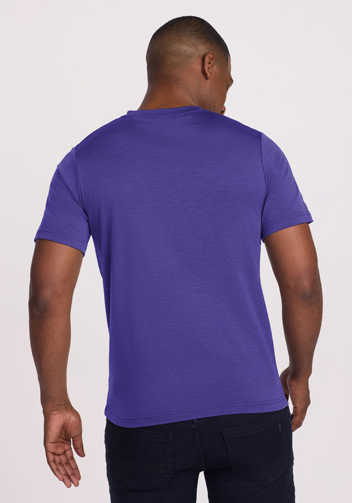 Man with his back to camera wears Woolx Endurance Tee - Berry Indigo and dark jeans against a plain background.