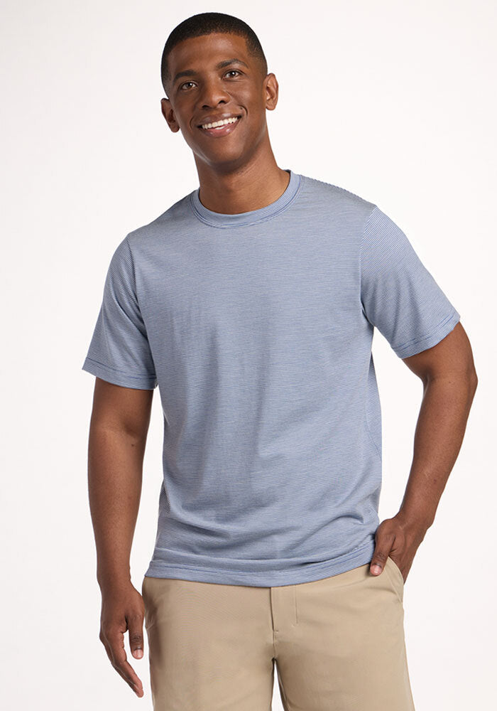 Smiling man in Woolx Endurance Tee - Blue Sand Mini Stripe and beige pants, standing against a white background. | Trell is 6’2”, wearing a size M