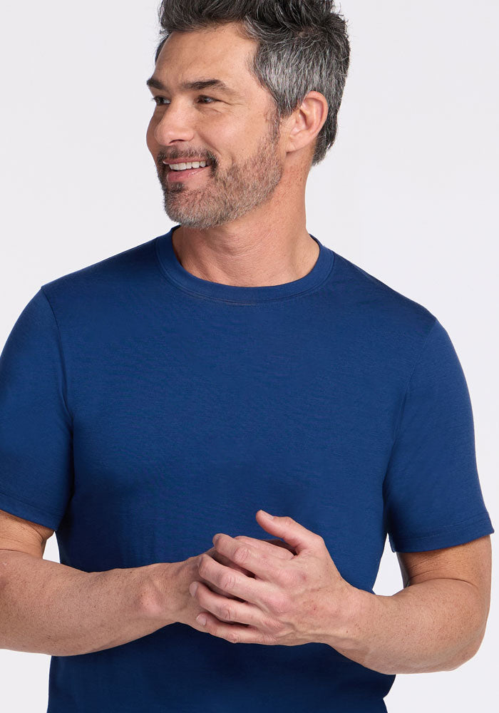 Smiling man in a Woolx Endurance Tee • Final Sale - Estate Blue, looking to the side with hands clasped.