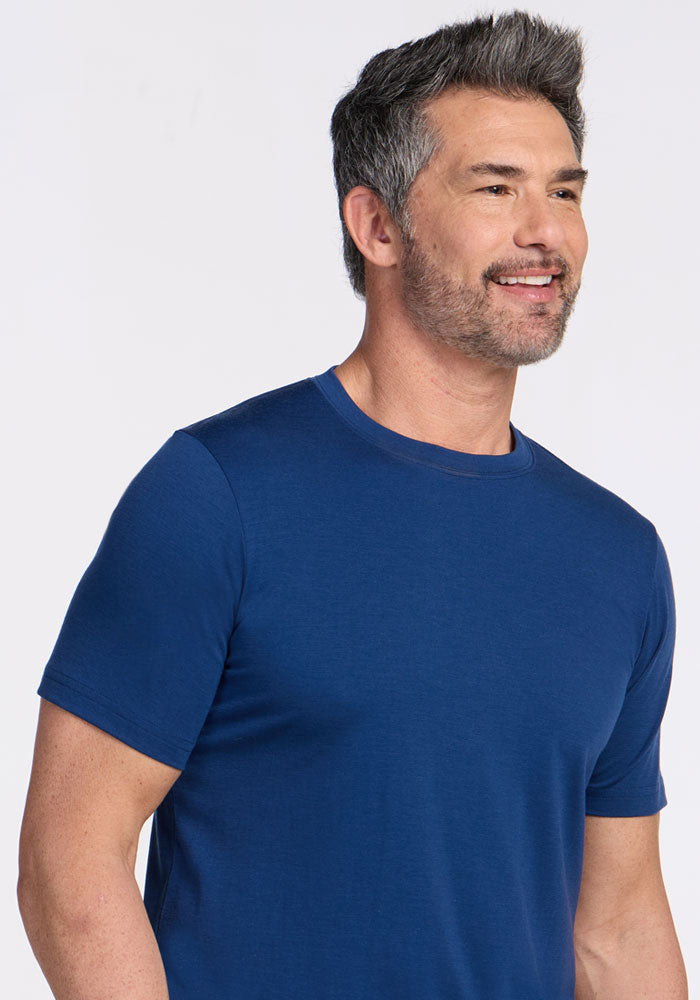 Man with short dark hair and beard wears Woolx Endurance Tee in Estate Blue, smiling and looking to the side.