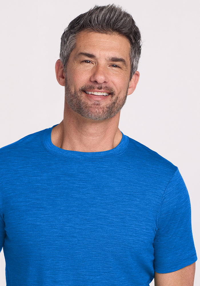 Smiling man with short gray hair and beard wears Woolx Endurance Tee • Final Sale - Glacial Blue against a plain background.