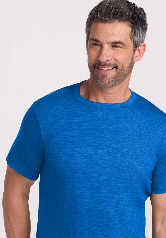 Smiling man with short gray hair in a Woolx Endurance Tee • Final Sale - Glacial Blue, against a light background.