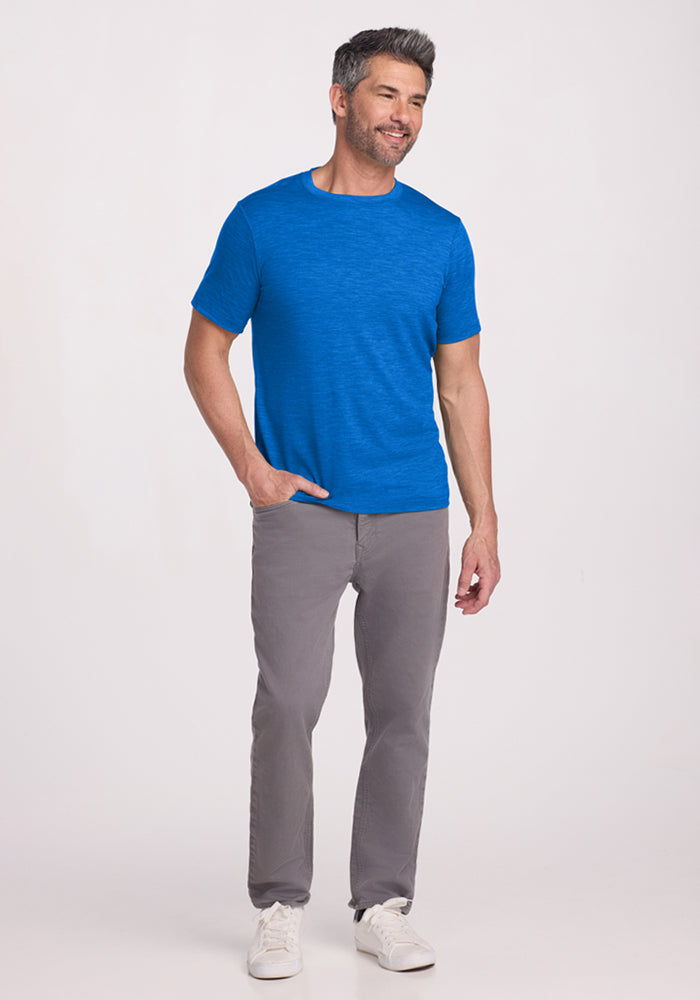 Man in a Woolx Endurance Tee in Glacial Blue stands smiling against a plain light background.