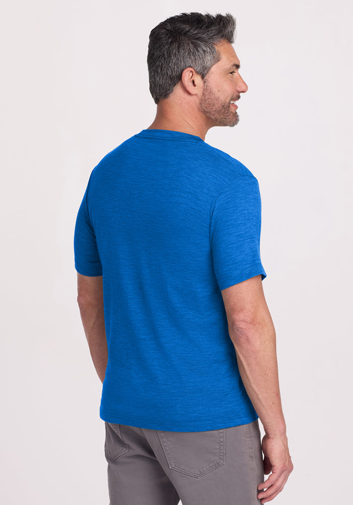 Man with short gray hair models the Woolx Endurance Tee in Glacial Blue, facing away and looking to the side.