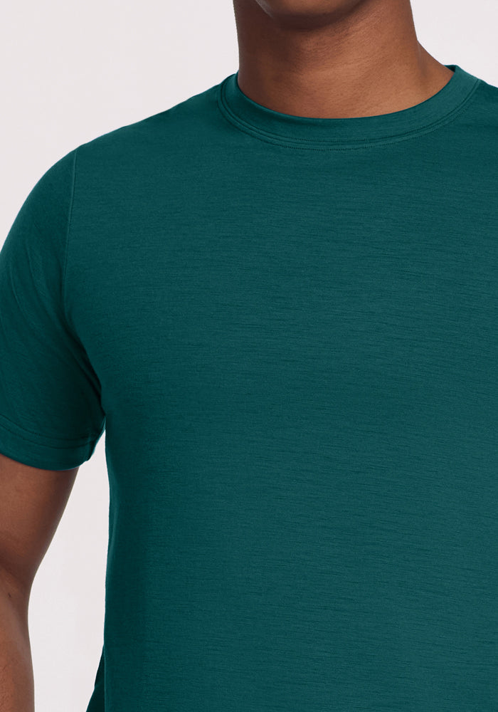 Person wearing the Woolx Endurance Tee in Riverbank Green, shown from shoulders to mid-torso against a plain background.