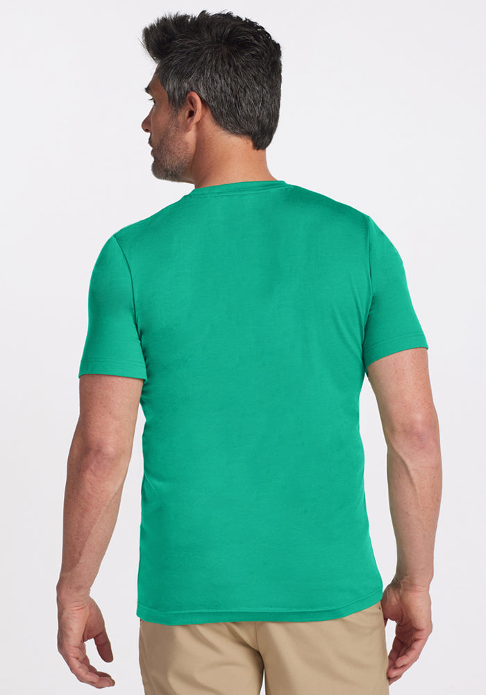 A man with short dark hair wears a Woolx Endurance Tee - Jungle and beige pants, standing with his back to the camera.