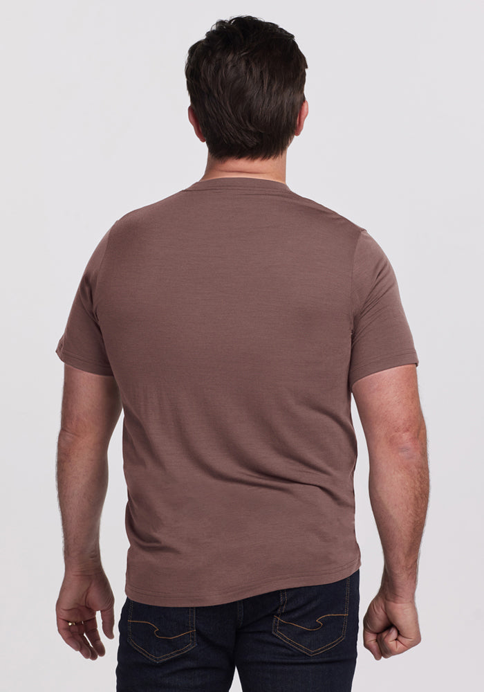 A man in a Woolx Endurance Tee - Peppercorn and dark jeans stands facing away against a plain light background.