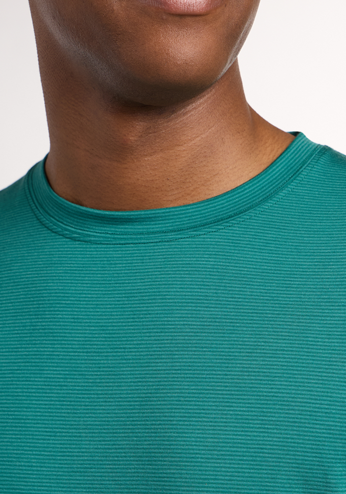 A close-up of a person wearing the Woolx Endurance Tee - Woodland Mini Stripe. The shot captures the lower face, neck, and upper chest, showcasing the soft merino fabric and striped pattern—perfect for those wanting comfortable performance wear.