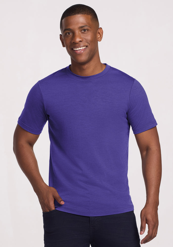 Smiling man in a Woolx Endurance Tee - Berry Indigo and dark pants, standing against a light background. | Trell is 6’2”, wearing a size M