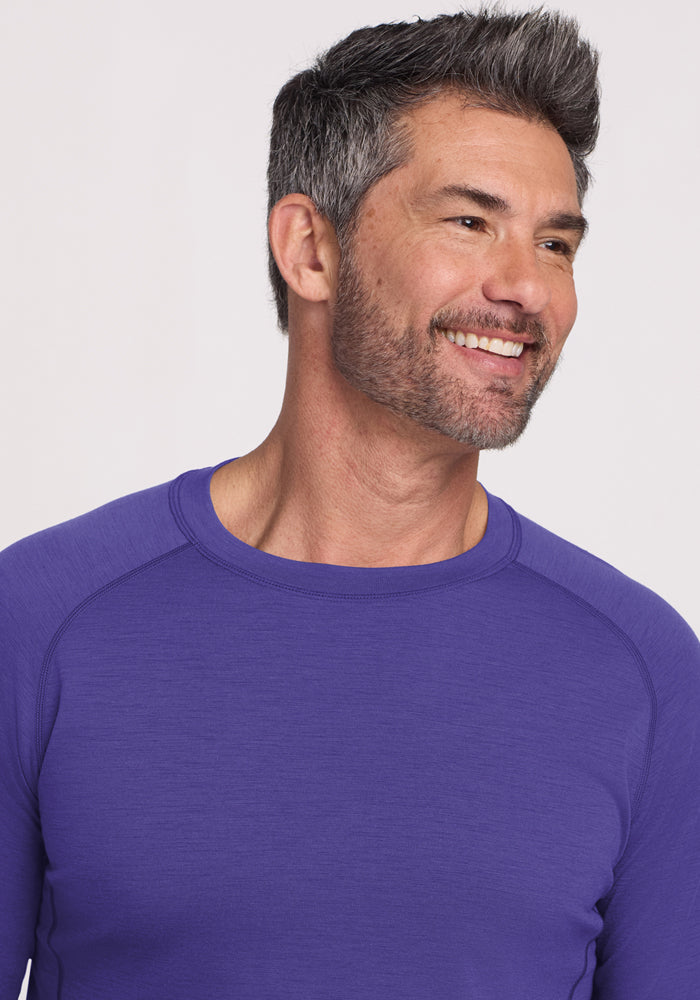 Smiling man with short gray hair in a Woolx Essential Tee - Berry Indigo, enjoying temperature-regulating comfort.