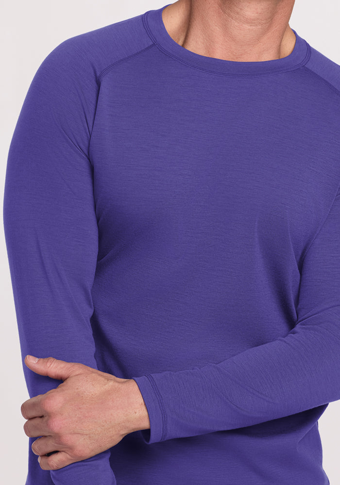 Someone wearing the Woolx Essential Tee - Berry Indigo crosses an arm over their body against a plain background.