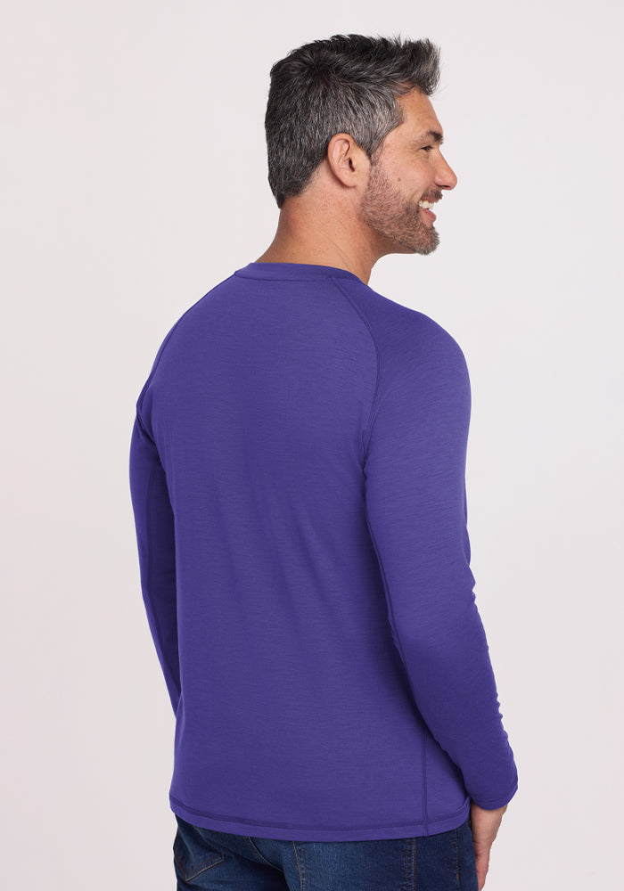 A man in a Woolx Essential Tee - Berry Indigo and blue jeans stands facing away, smiling.