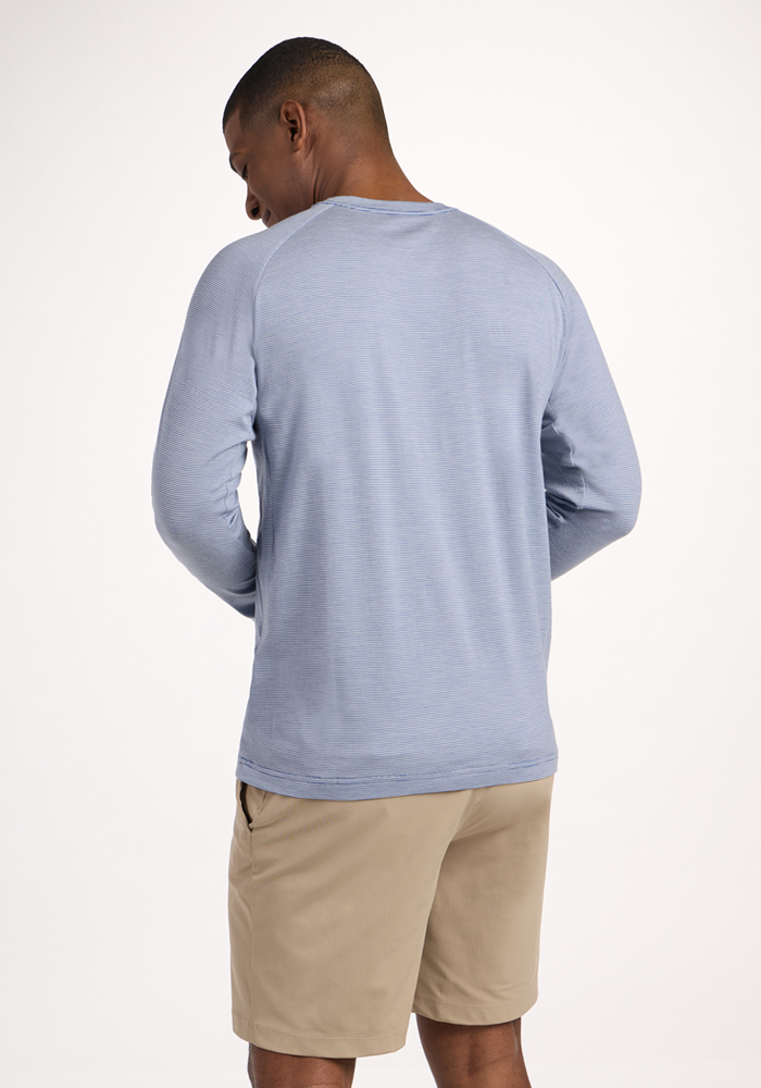A man faces away from the camera, wearing the Woolx Essential Tee in Blue Sand Mini Stripe and beige shorts, set against a plain light background.