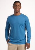 A man smiles while wearing the Woolx Essential Tee - Coastal Mini Stripe, a lightweight blue crew-neck shirt, and beige pants, with one hand in his pocket against a plain white background. | Trell is 6’2”, wearing a size M