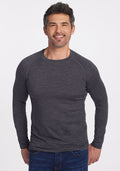 A smiling man in Woolx’s Essential Tee • Final Sale - Cinder Melange stands before a white background in blue jeans.
