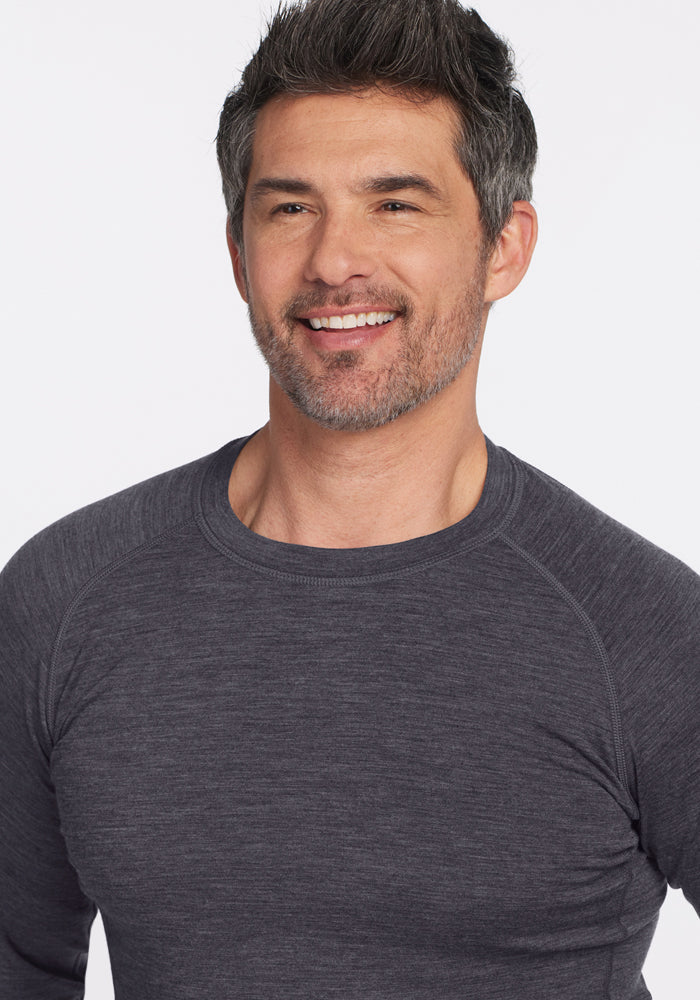 Smiling man in a Woolx Essential Tee • Final Sale - Cinder Melange, with short dark hair and beard, plain background.