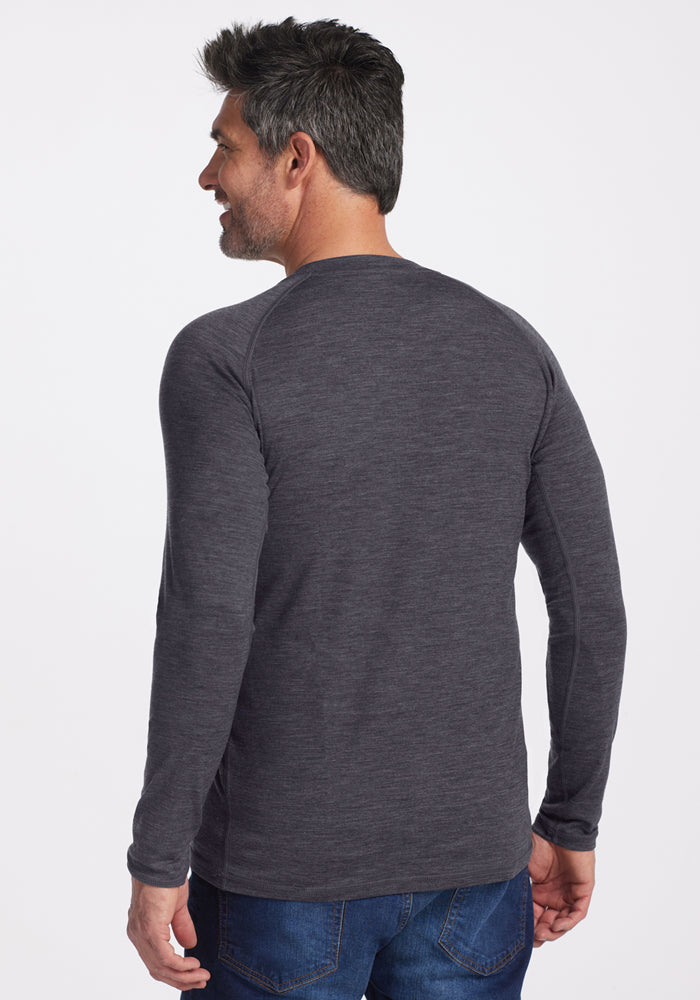 Man with short dark hair in a Woolx Essential Tee in Cinder Melange, facing away and smiling.