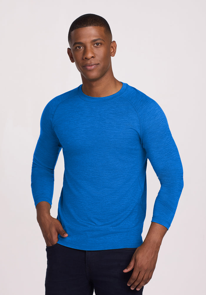 Man wearing a Woolx Essential Tee in Glacial Blue and dark pants, standing against a light background, facing the camera.
