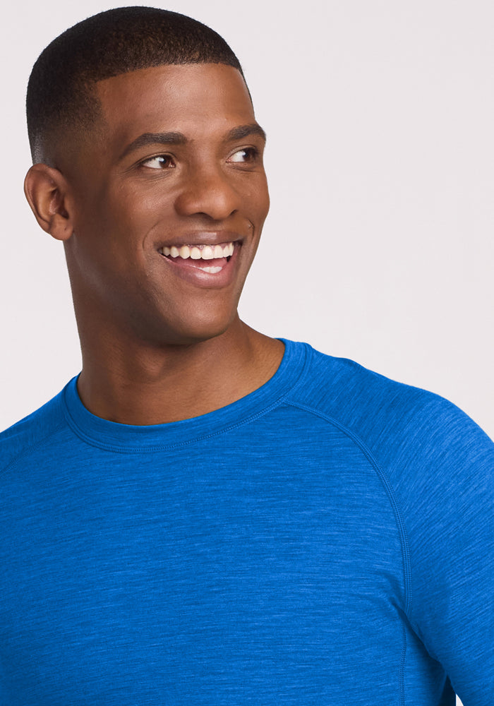 Man smiling, wearing the Woolx Essential Tee in Glacial Blue against a light background. Final Sale.