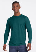 Man wearing a Woolx Essential Tee in Riverbank Green, standing against a plain white background and smiling slightly.