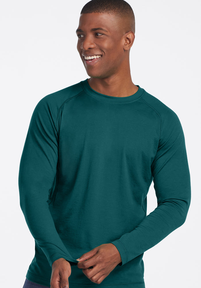 Man smiling in a Woolx Essential Tee • Final Sale - Riverbank Green, known for its temperature regulating qualities.