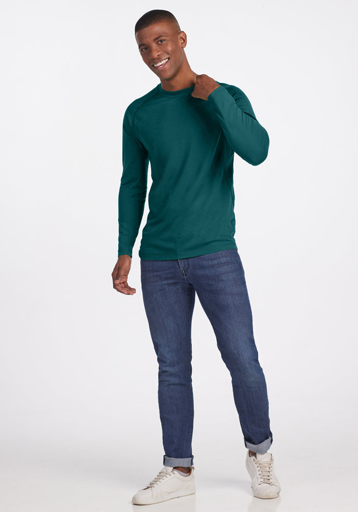 A man in a Woolx Essential Tee in Riverbank Green smiles, enjoying its temperature-regulating comfort.