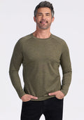 Man smiling, wearing the Woolx Essential Tee in Sage Olive Melange and black pants, hands in pockets.